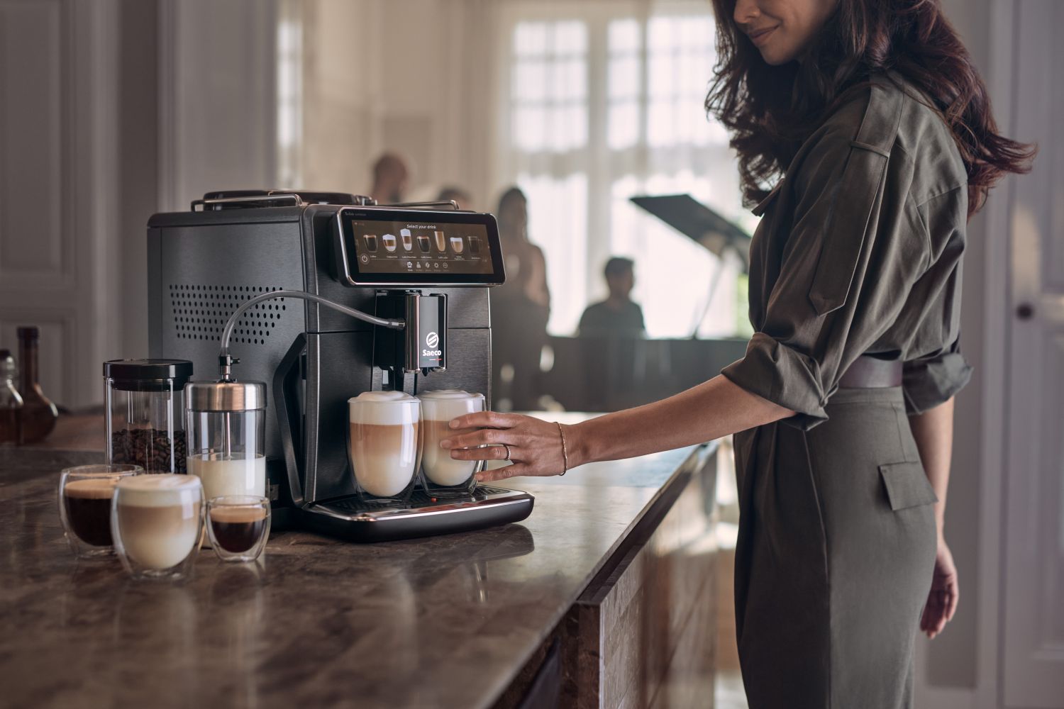 Eine Frau nimmt sich einen Kaffee von der Kaffeemaschine